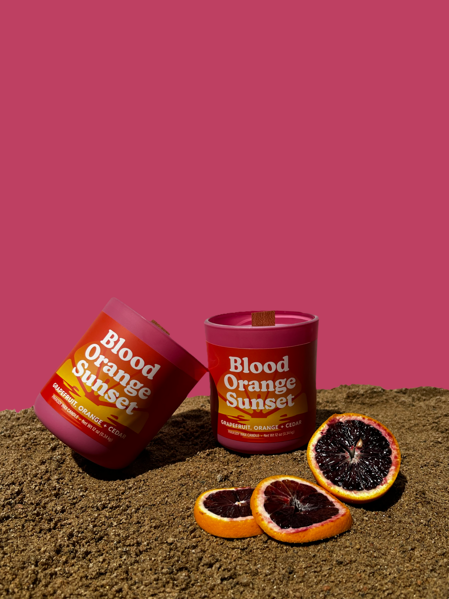 Two 12oz wood wick candles with pink jars With the "Blood orange sunset" label scented with Grapefruit, Orange & Cedar.