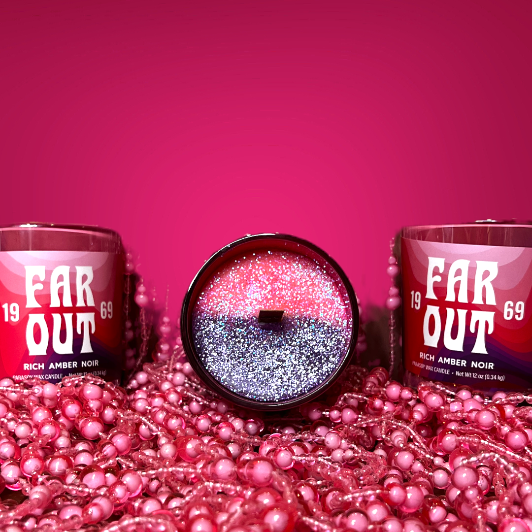 Two candles with 'Far Out' and a number '19' and '69' on the label, surrounded by pink confetti and decorative beads.