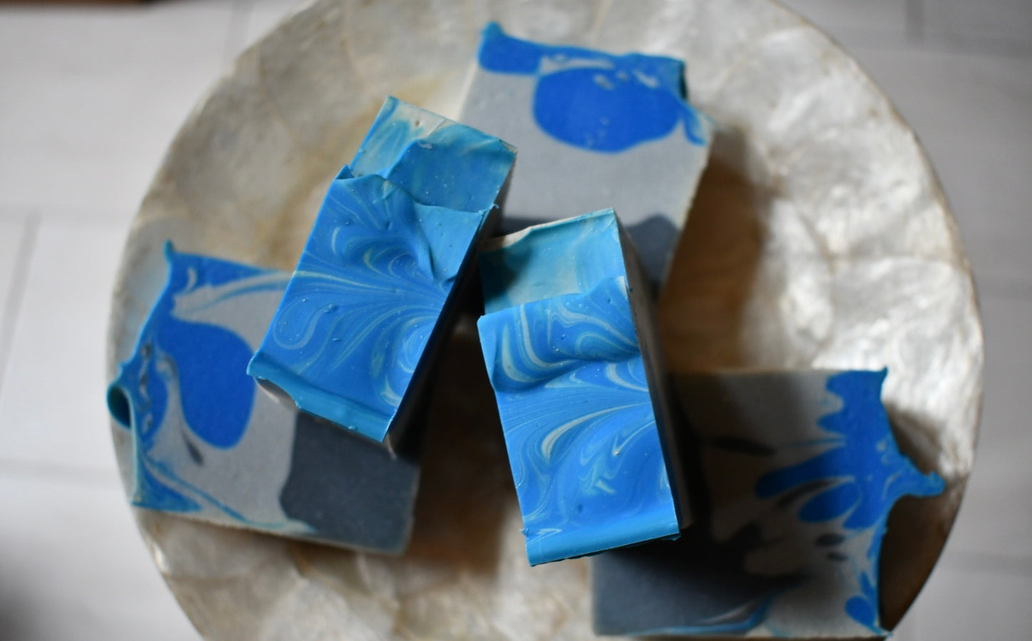 Blue and gray marbled soap bars on a stone surface