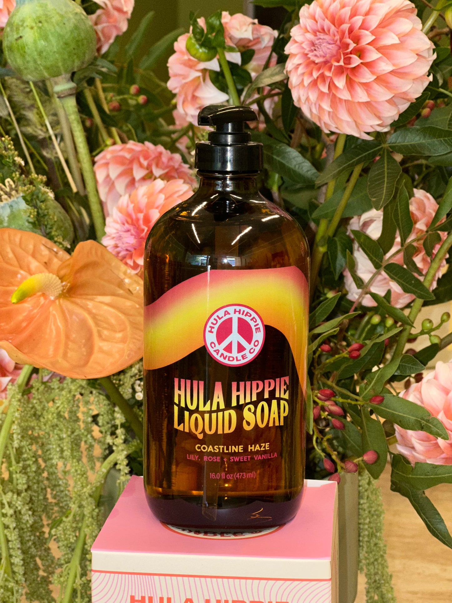 Hula Hippie liquid soap bottle with flowers in the background