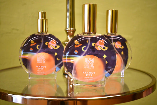 Three perfume bottles with gold caps on a reflective surface against a green background