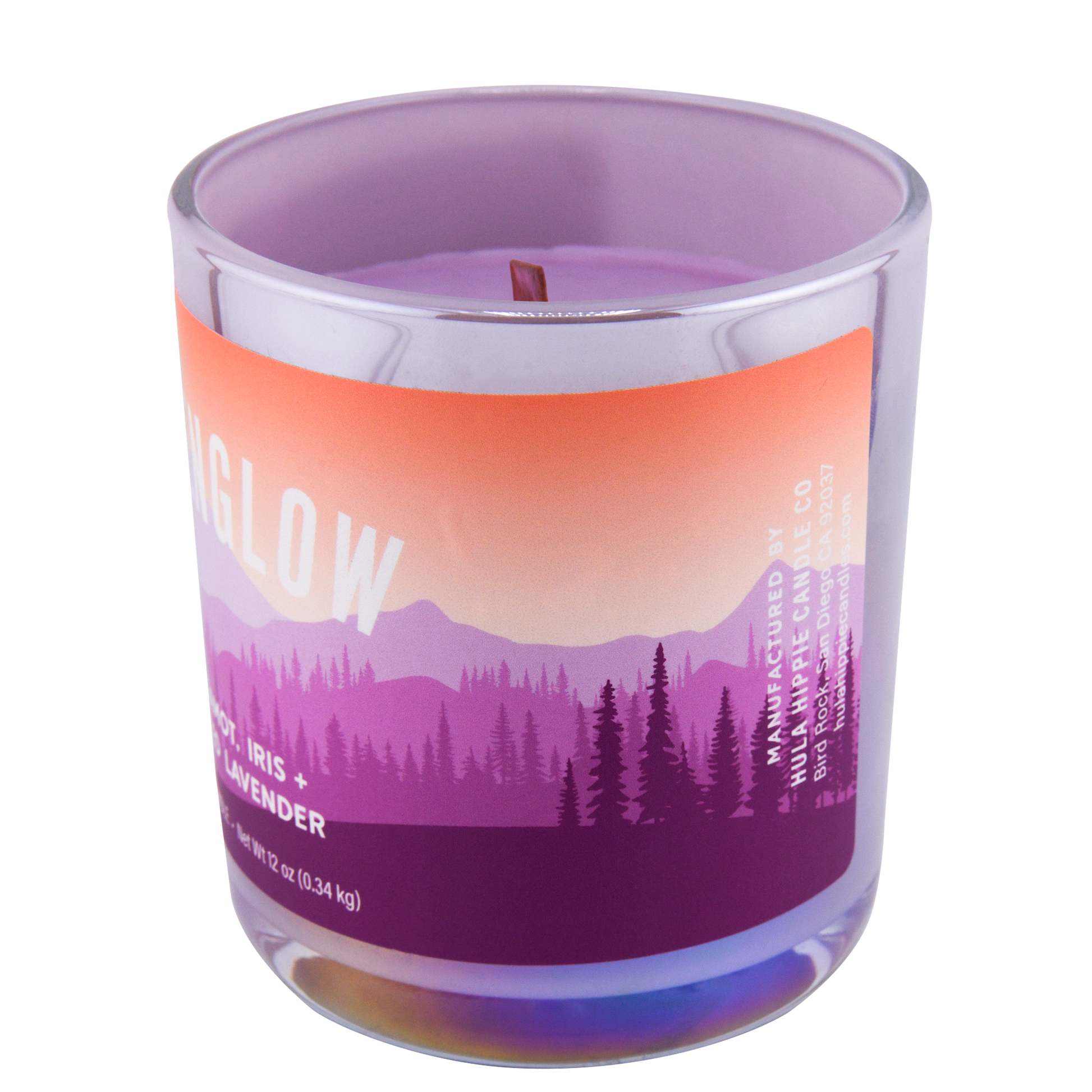 Right-side view of a scented candle labeled "Alpenglow" and scented notes of bergamot, iris, and frosted lavender, in a clear glass jar with a purple to orange gradient design and a forest scene.