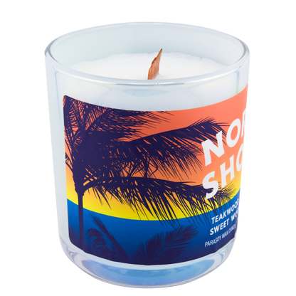 Left-side view of a scented candle in an iridescent jar labeled "North Shore" with notes of teakwood and jasmine.