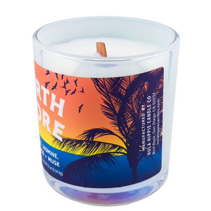 Right-side view of a scented candle in an iridescent jar labeled "North Shore" with notes of teakwood and jasmine.