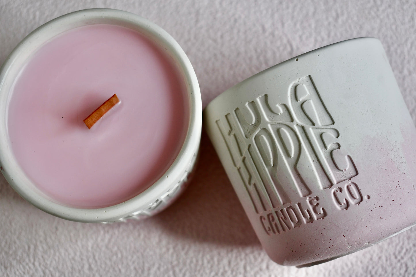 Pink candle in a white container with 'Hula Hippie Candle Co.' branding on a light background