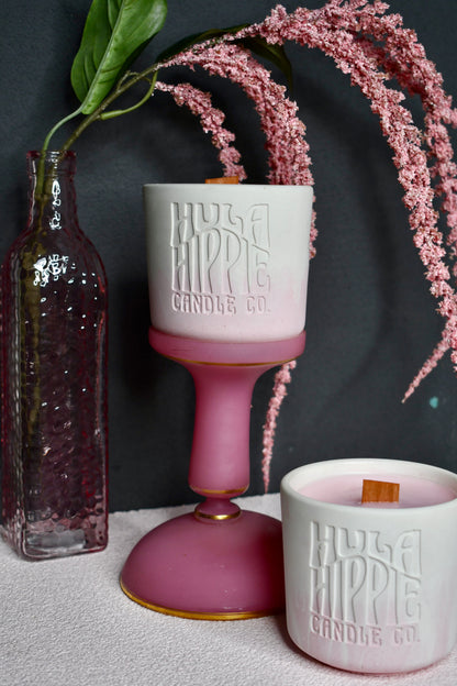 Two pink candles with 'Hula Hippy Candle Co' branding on a dark background.